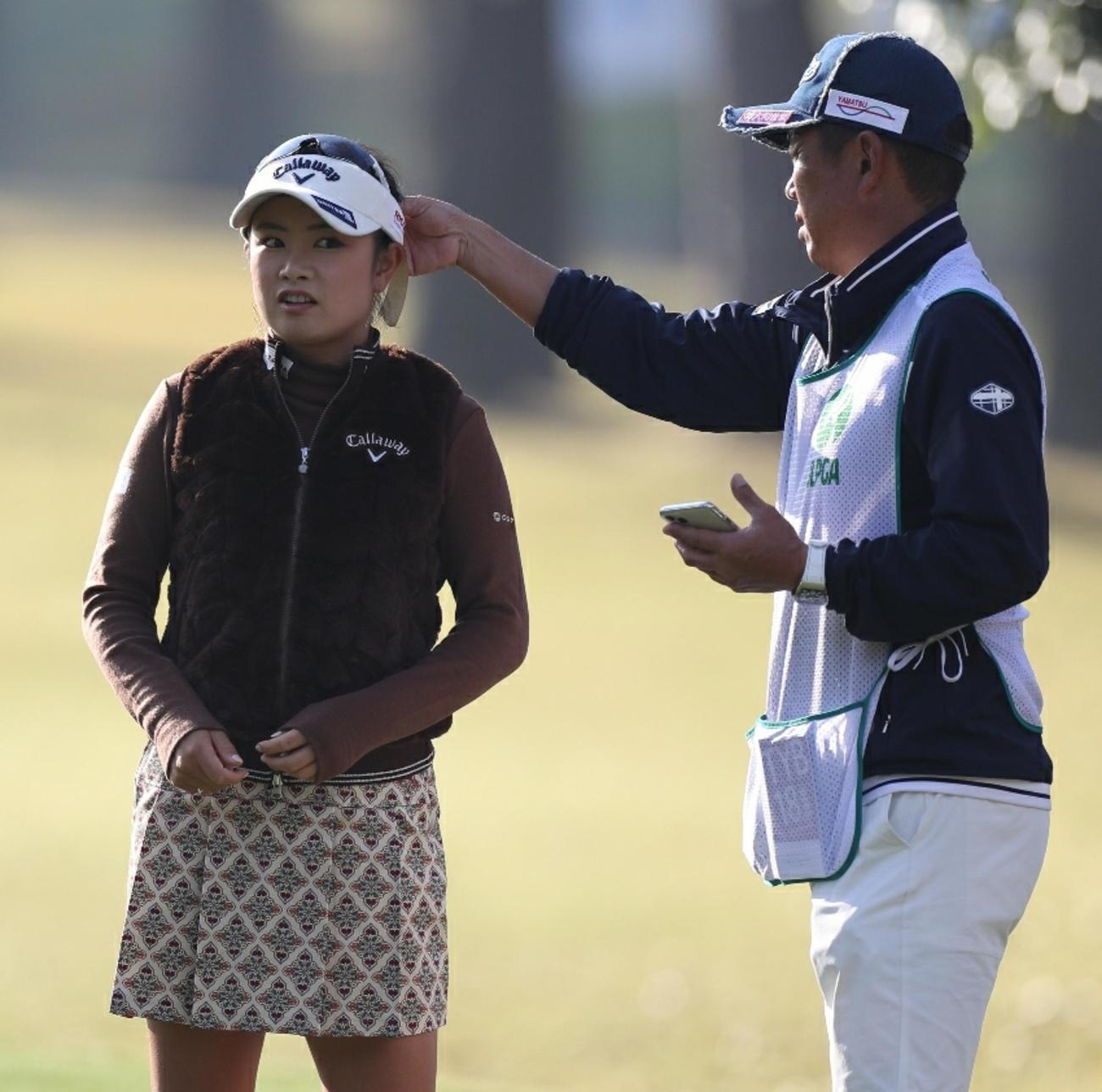 ラウンド前、キャディーにリボンをなおしてもらう河本結（撮影・狩俣裕三）