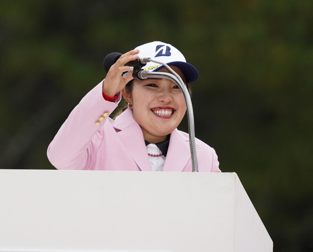 表彰式での優勝スピーチでマイクの位置が高く笑顔をみせる古江彩佳（撮影・清水貴仁）