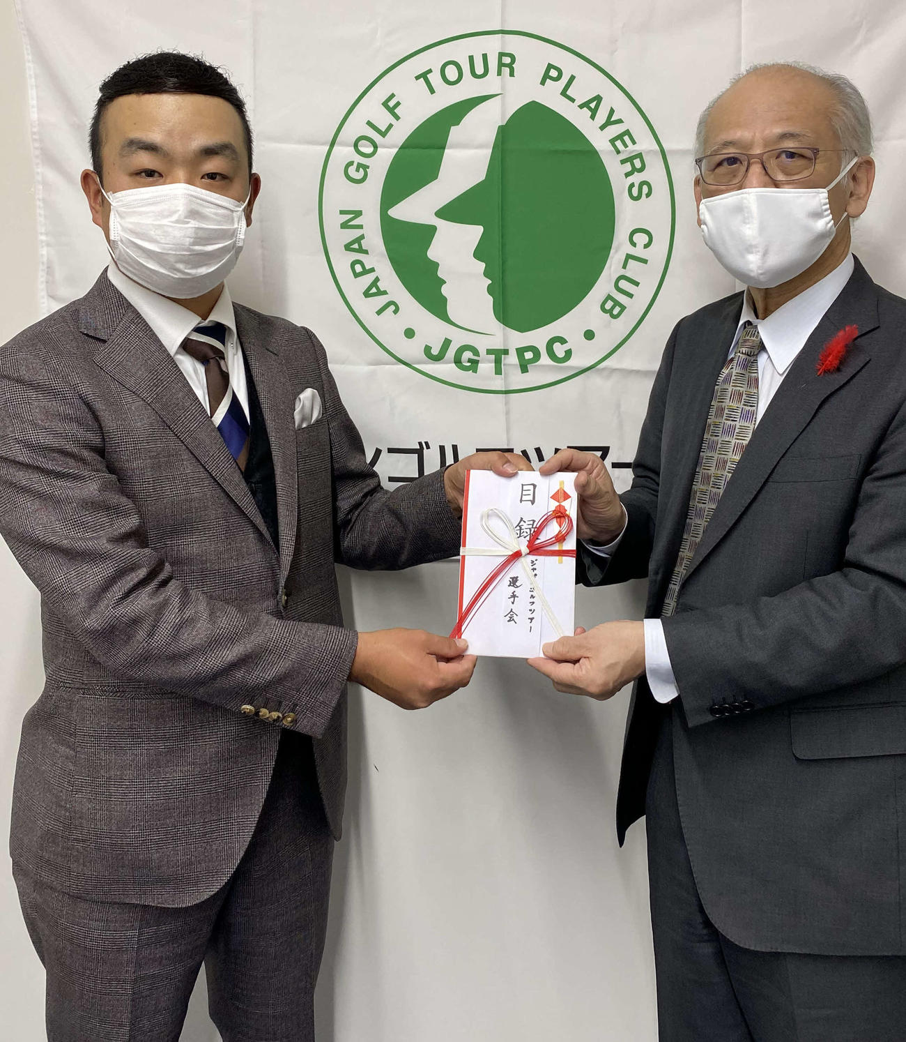 社会福祉法人中央共同募金会の渋谷篤男氏（右）に目録を贈呈するJGTO選手会長の時松隆光（提供写真）