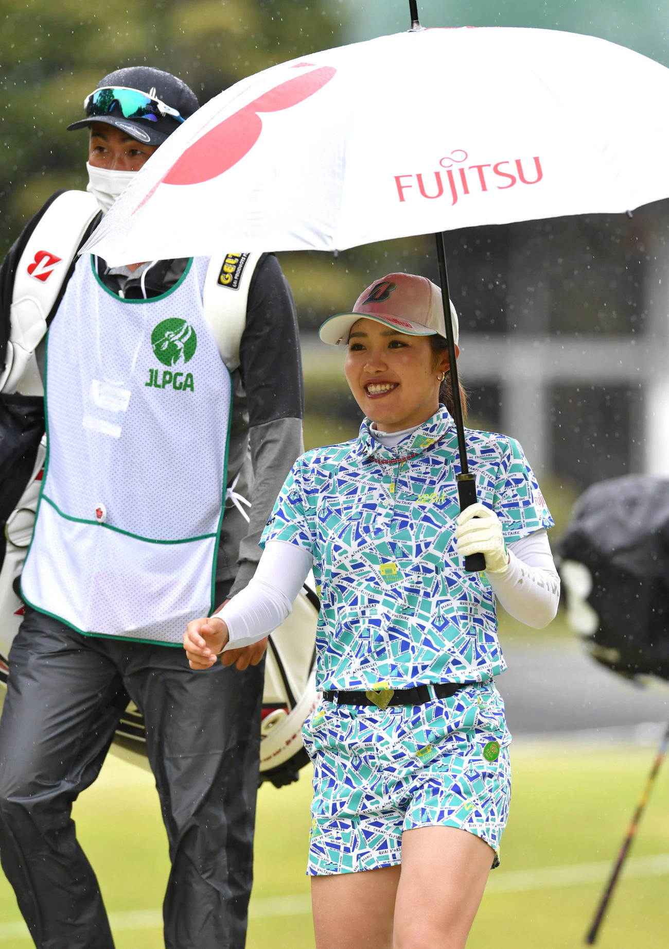 1番、傘を手に笑顔で第2打へ向かう古江（撮影・岩下翔太）