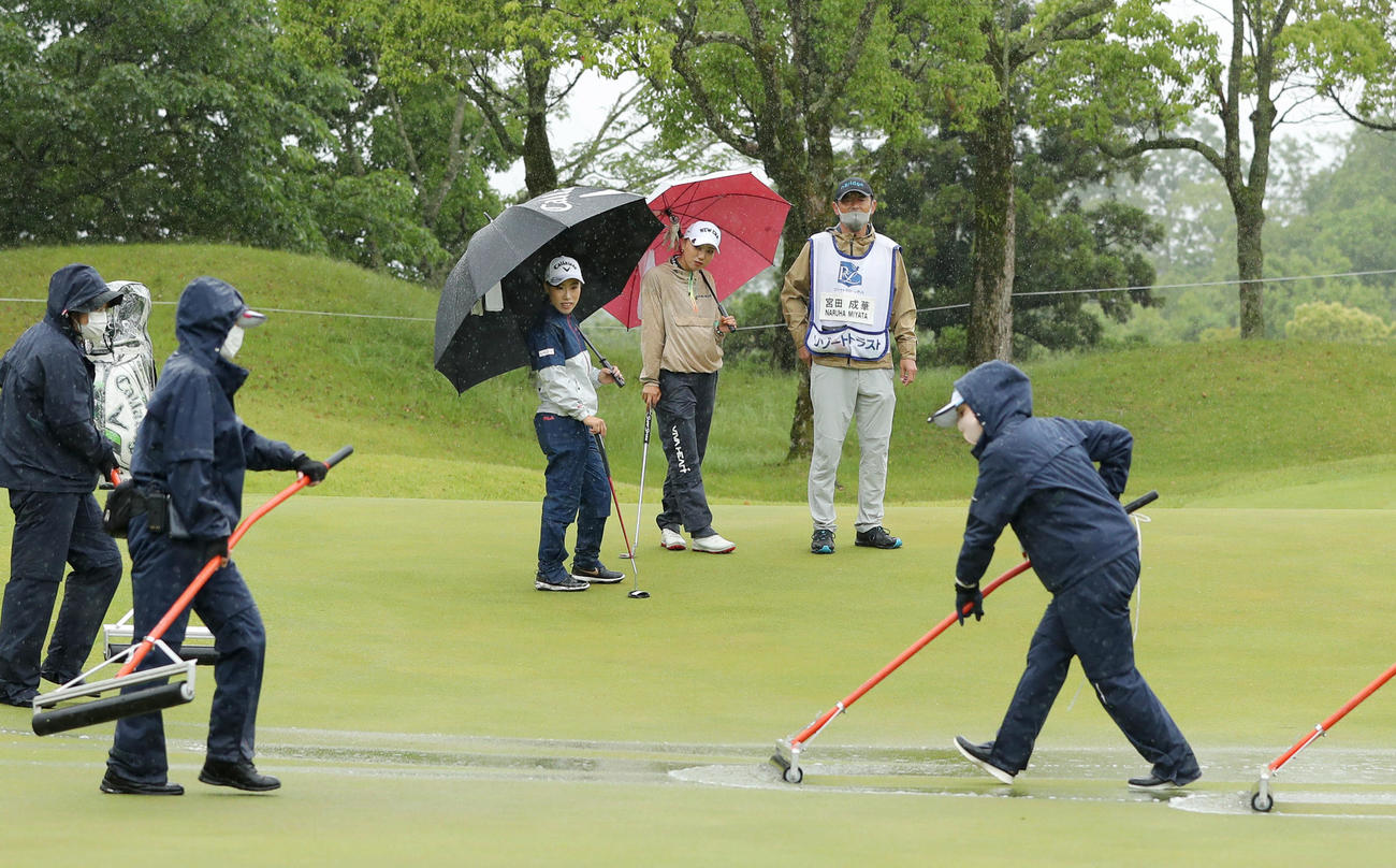 1番、グリーンにたまった水を取り除く大会スタッフ（手前）を見つめる宮田成華（後方中央）と木村彩子（同左）ら（撮影・前田充）