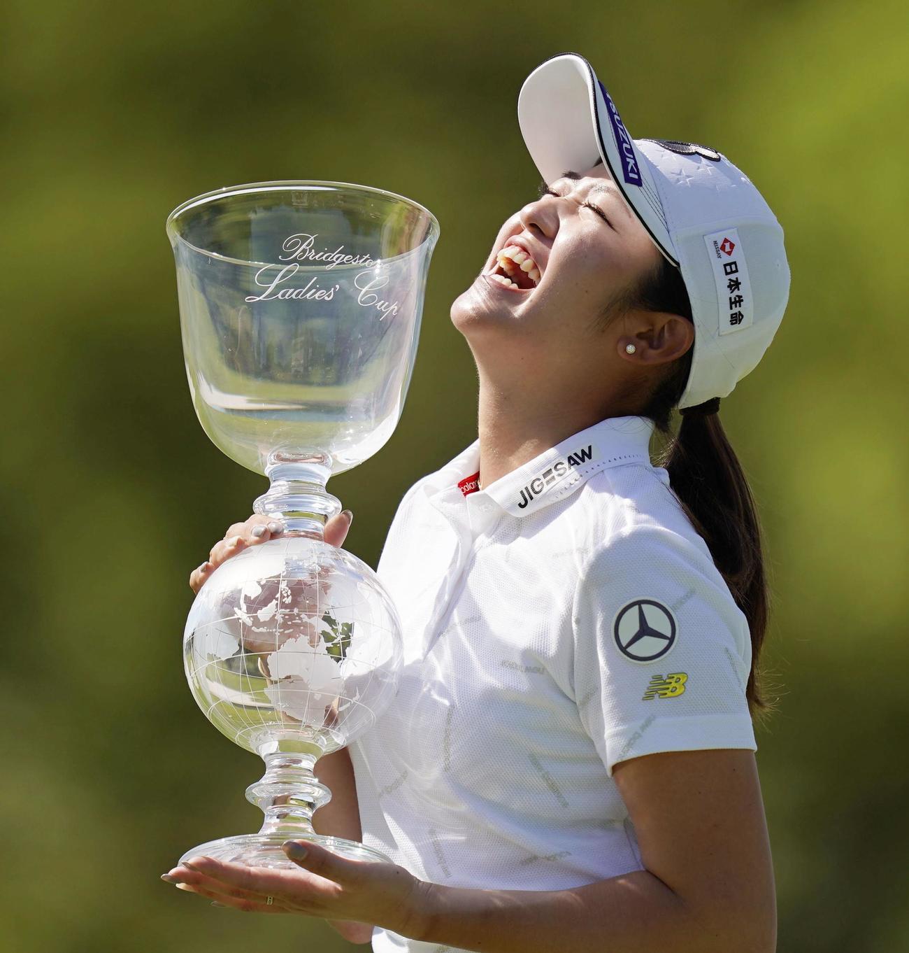 通算15アンダーで優勝し、カップを手に笑顔の稲見萌寧（共同）