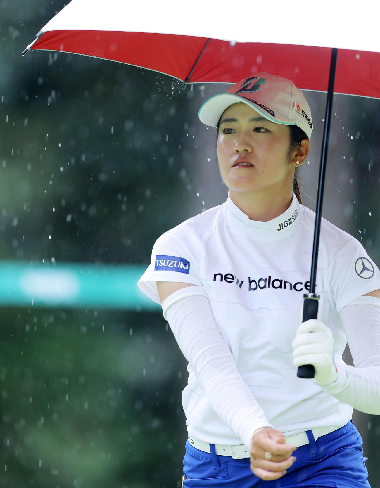 12番、雨が降りだし、傘を差しながら移動する稲見（撮影・河田真司）