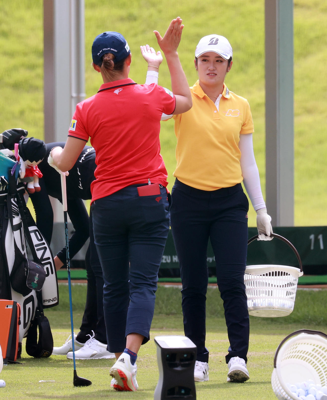 練習ラウンド前、ドライビングレンジで渋野（左）とハイタッチする稲見（撮影・浅見桂子）