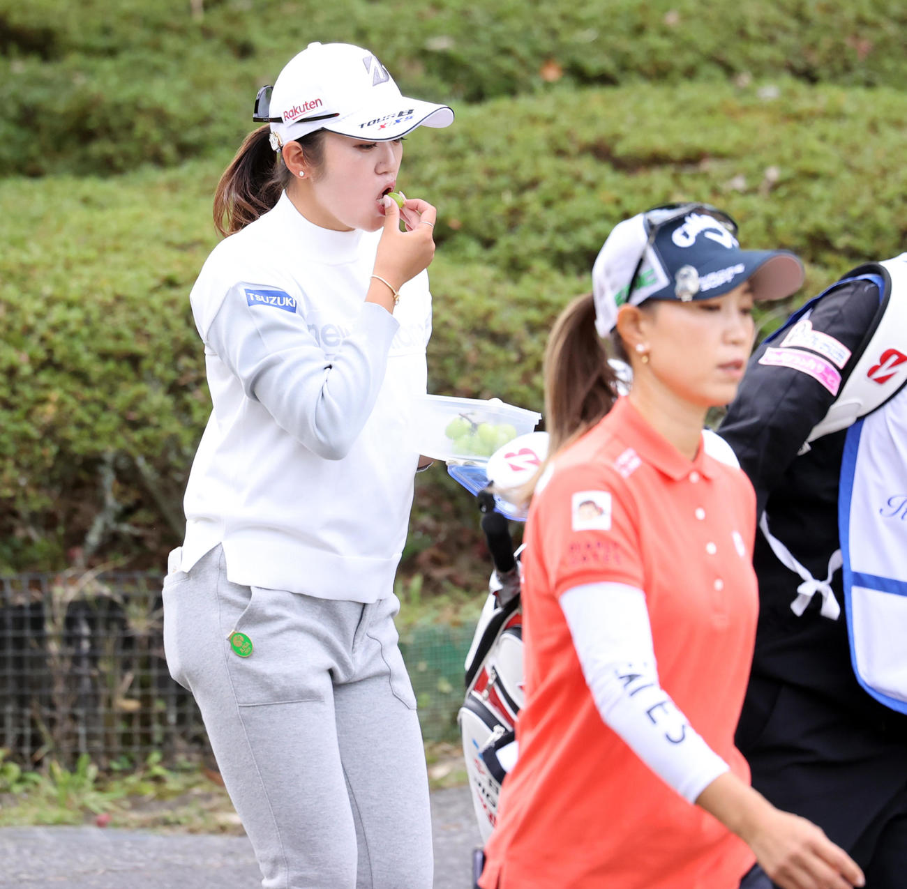 6番、ティーショット後、マスカットをほおばる稲見。手前は上田（撮影・浅見桂子）