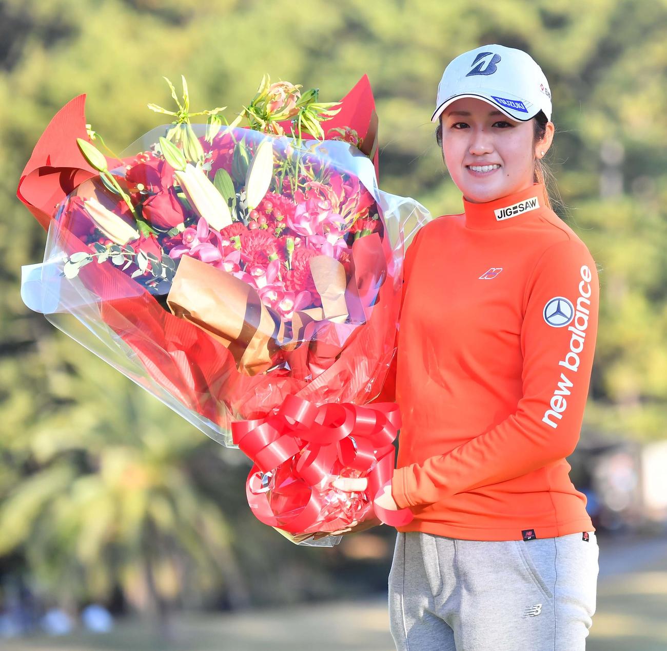 賞金女王の稲見萌寧は花束を手に笑顔を見せる（撮影・上田博志）