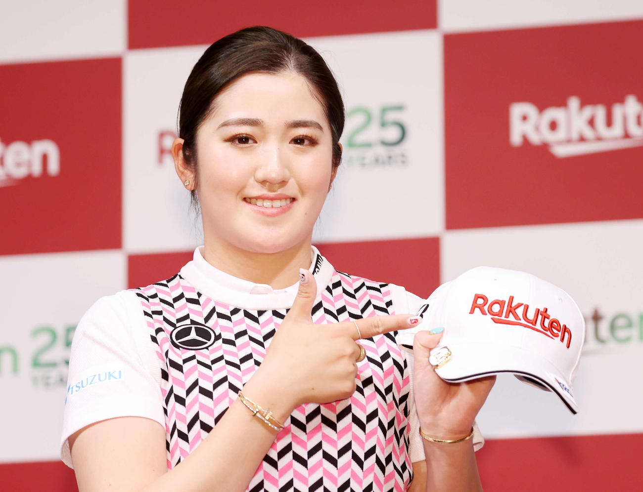 楽天ロゴ入りキャップを手に笑顔を見せる稲見萌寧（撮影・鈴木正人）
