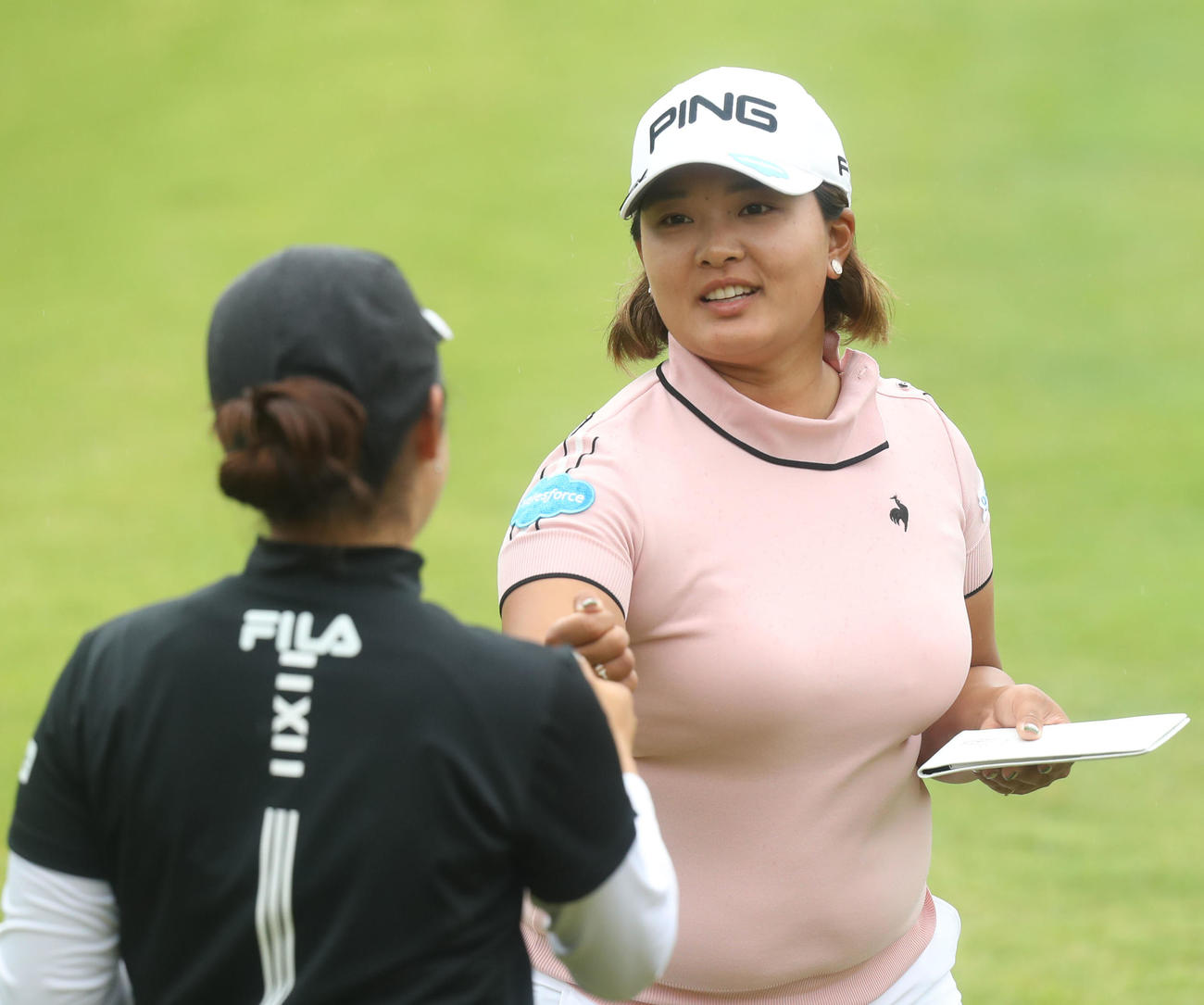 18番、ホールアウトし、天本（手前）とグータッチをする鈴木（撮影・屋方直哉）