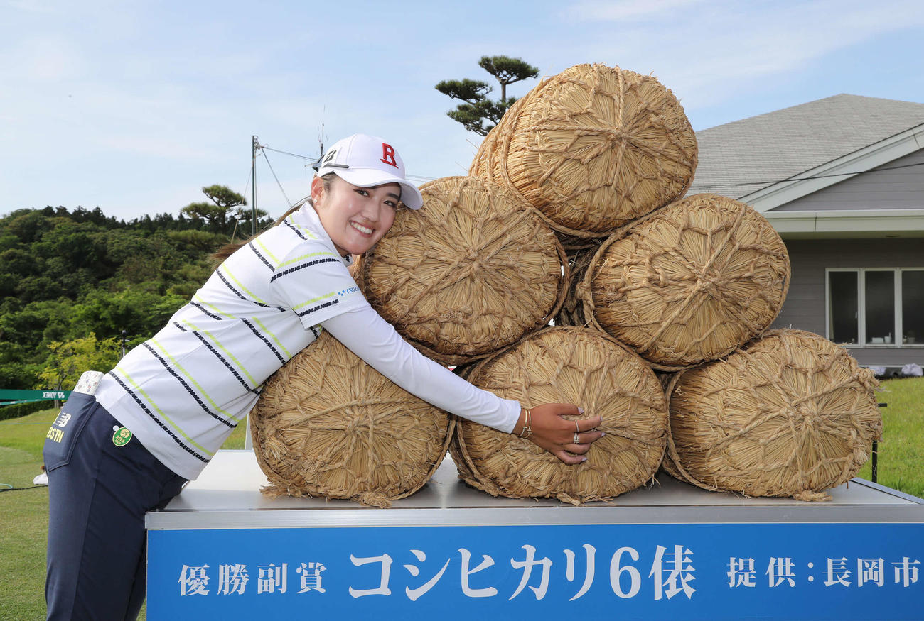 優勝し副賞の米俵と写真に納まる稲見（撮影・丹羽敏通）