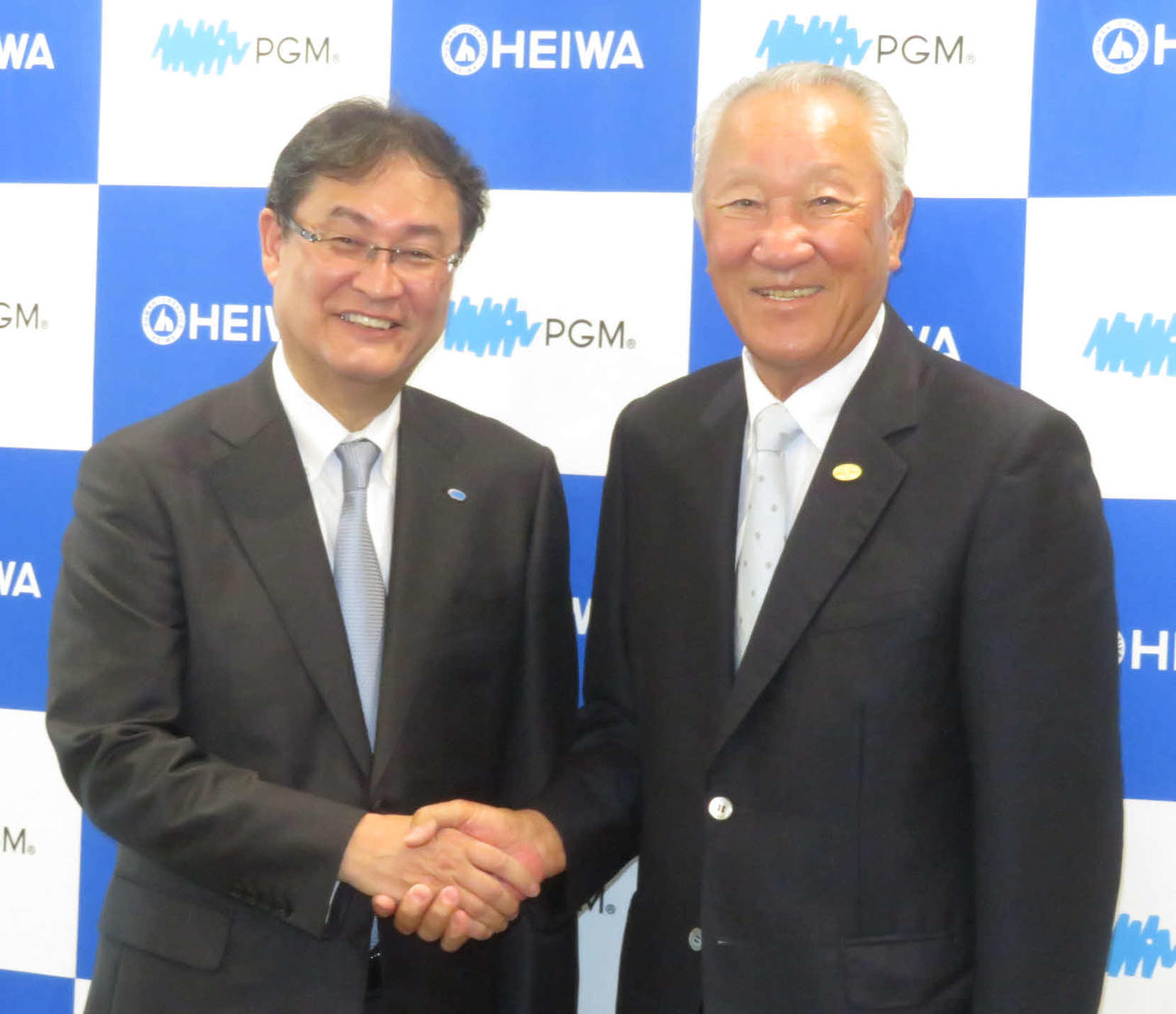 会見後に笑顔で握手を交わすJGTOの青木会長（右）と、パシフィックゴルフマネージメントの田中社長