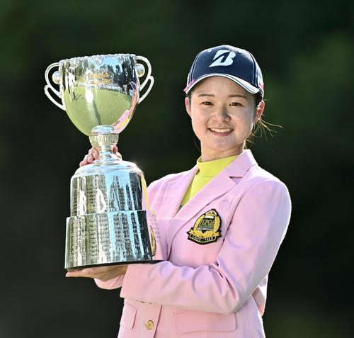 通算16アンダーで大会史上最年少優勝を果たし、カップを手に笑顔の川崎春花＝城陽C（共同）