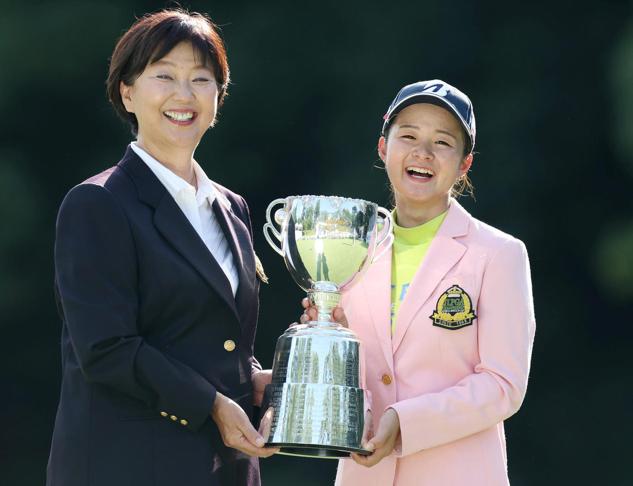 初優勝を果たし、JLPGAの小林会長（左）と笑顔で優勝トロフィーを手にする川崎（撮影・前田充）