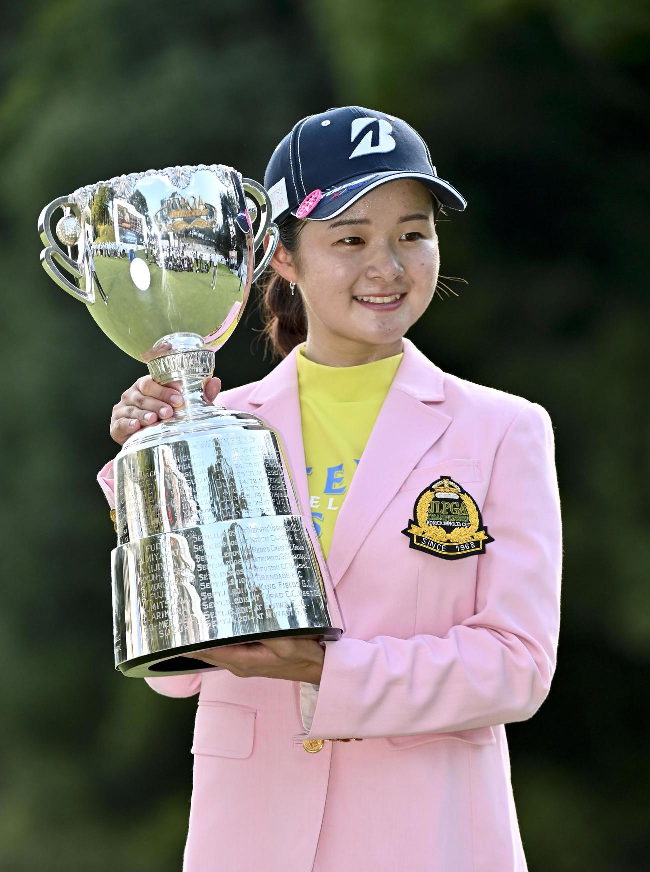 日本女子プロ選手権でツアー初優勝を果たし、カップを手に笑顔の川崎春花（共同）