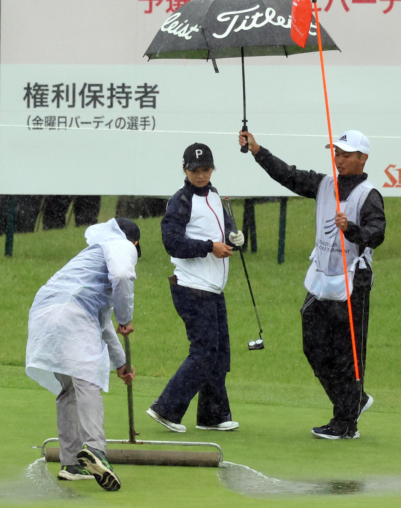 9番、大雨でグリーンにたまった水を吐き出すスタッフを見つめる菊地（中央）（撮影・狩俣裕三）