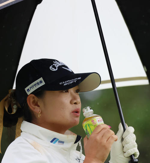 1番、ティーショットを放った後、熱いお茶を飲みフェアウエイに向かう河本（撮影・狩俣裕三）