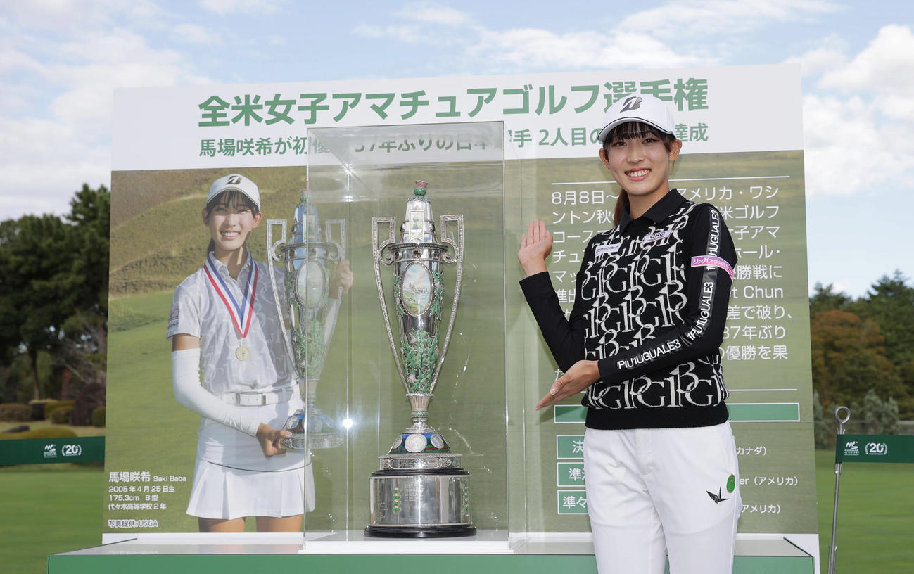 展示された全米女子アマチュアゴルフ選手権の優勝トロフィーと笑顔で写真に納まる馬場（撮影・前田充）