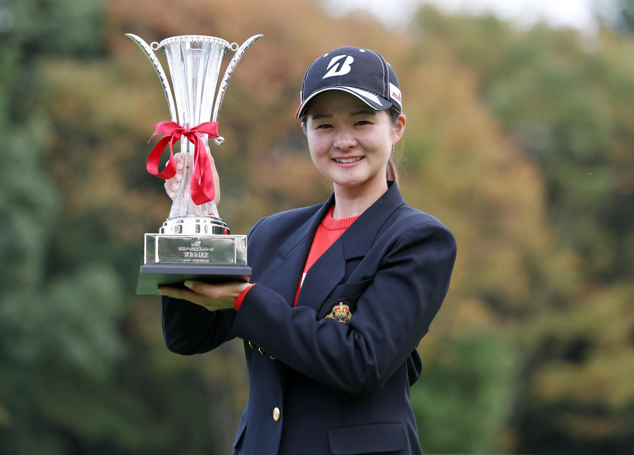 通算15アンダーで優勝し、笑顔で優勝トロフィーを掲げる川崎（撮影・前田充）