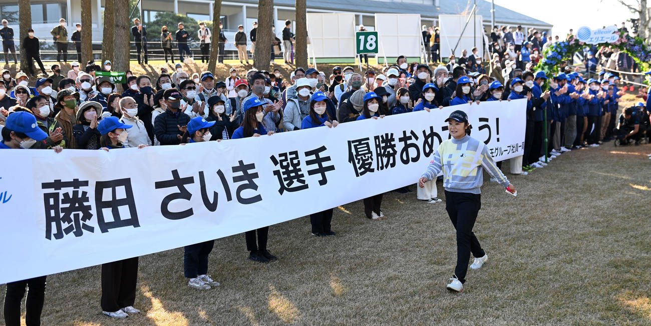 優勝を祝福する応援幕の前を通り表彰式に向かう藤田（撮影・前岡正明）
