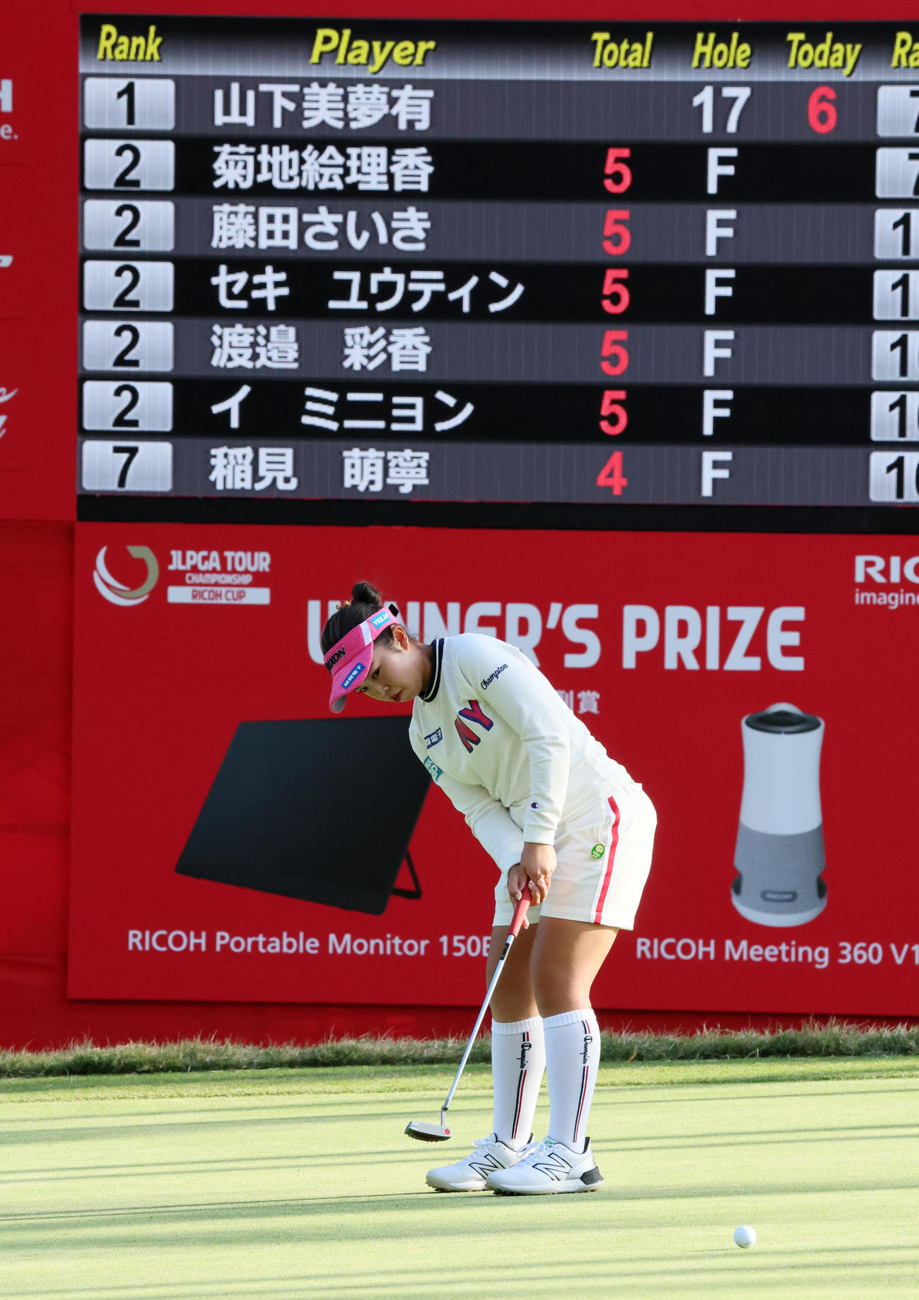 18番、初日首位を表示するスコアボードを背にパットを打つ山下美夢有（撮影・加藤哉）