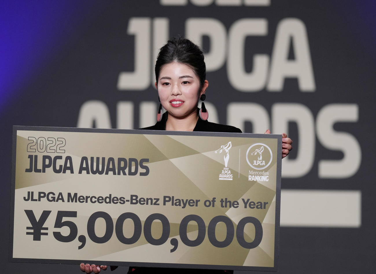 JLPGAアワードで年間最優秀選手に選ばれ、賞金ボードを手に笑顔を見せる山下（撮影・狩俣裕三）