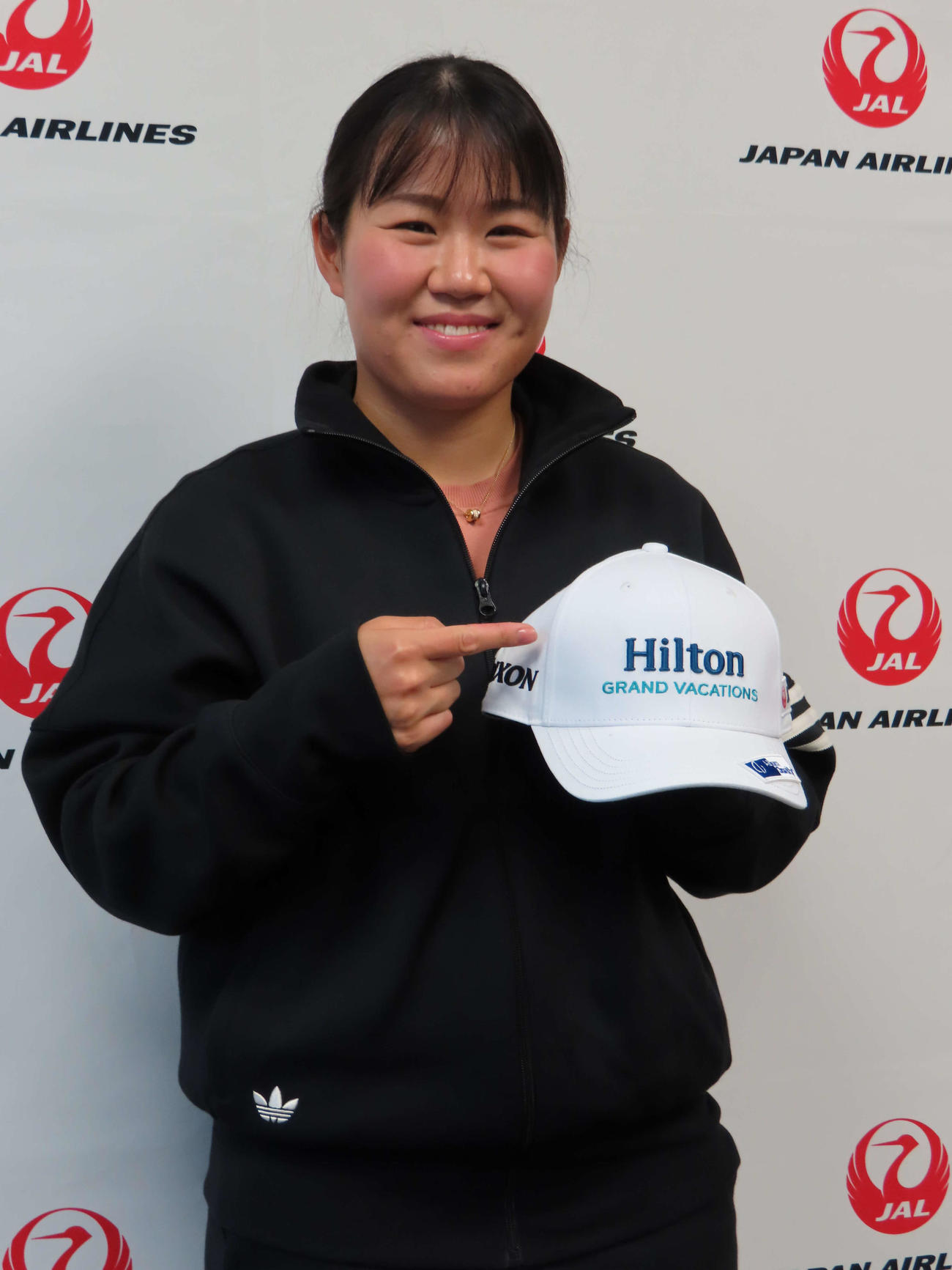 女子ゴルフの米ツアー開幕戦出発前に取材に応じる畑岡奈紗。新スポンサーロゴ入りのキャップを持ち笑顔で撮影に応じる（撮影・近藤由美子）