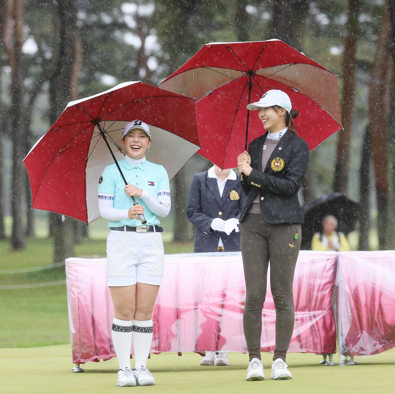 強い風雨の中、表彰式で笑顔を見せる優勝の吉田（左）とベストアマチュアの馬場（撮影・足立雅史）