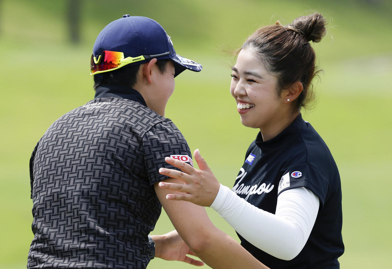 通算18アンダーで今季2勝目を挙げ、2位の岩井明愛（左）と健闘をたたえ合う山下美夢有（共同）