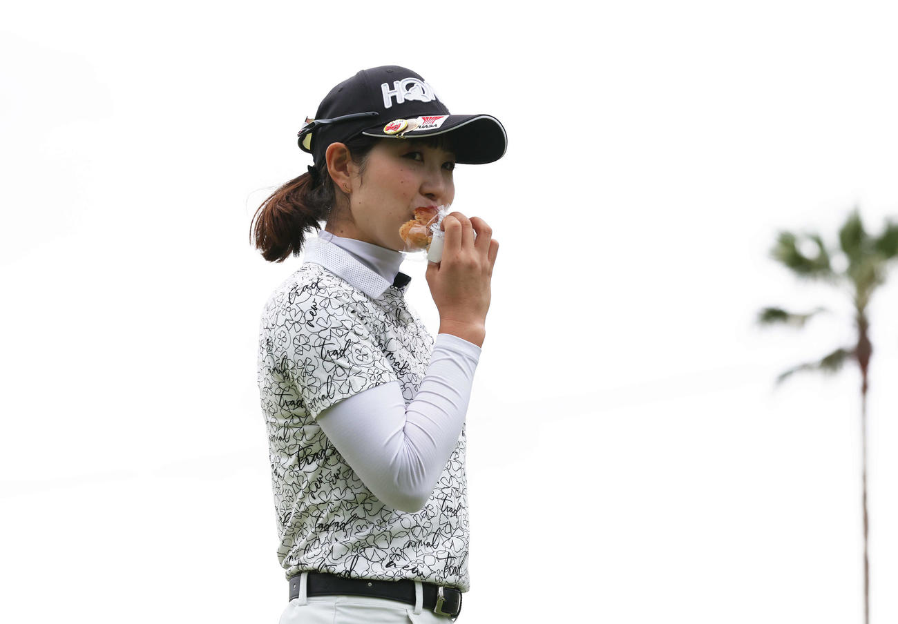 1番、ティーショットを放ち、食べながら移動する蛭田（撮影・宮地輝）