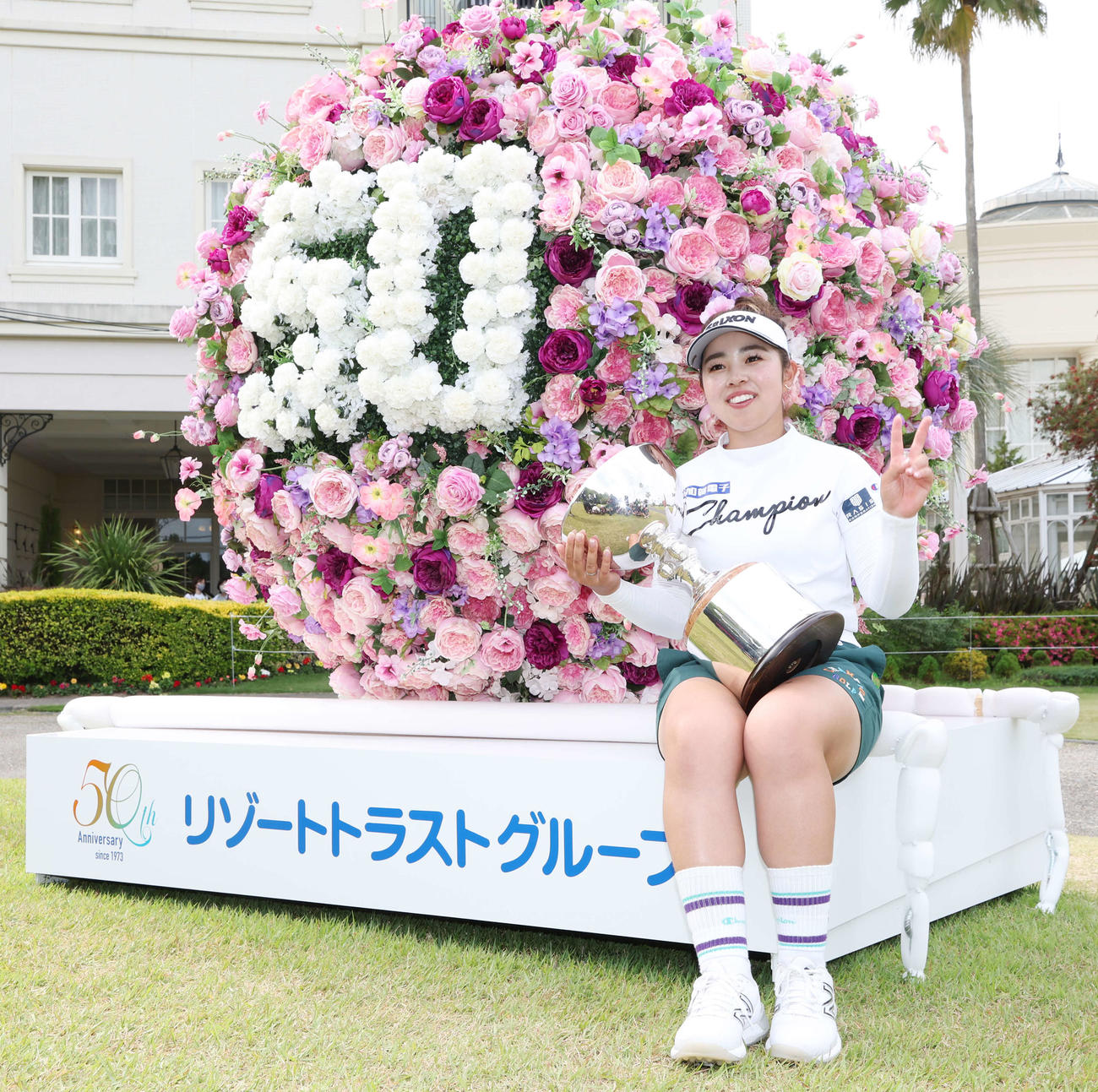 優勝カップを膝に笑顔でピースをする山下（撮影・宮地輝）