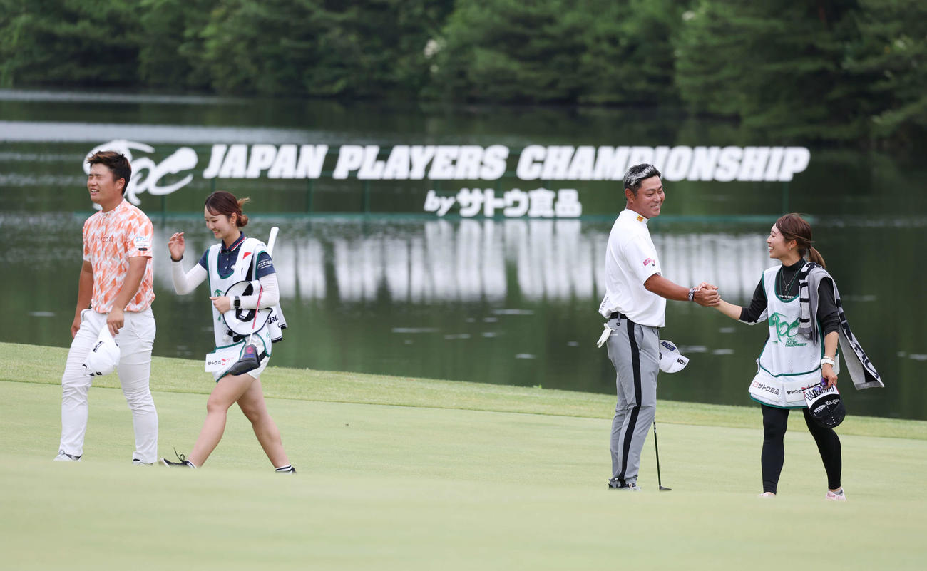 プレーオフを制して優勝し、キャディーと笑顔で握手する谷原（右）と敗れ悔しがる長野（撮影・宮地輝）