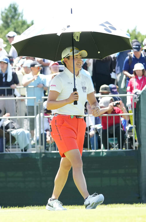 1番、ティーショットを終えた岩井明は傘をさして歩き出す(撮影・小沢裕)