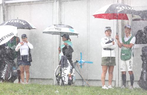 2日目　12番、豪雨で中断し雨宿りする左から小祝、鈴木、桜井（撮影・黒川智章）