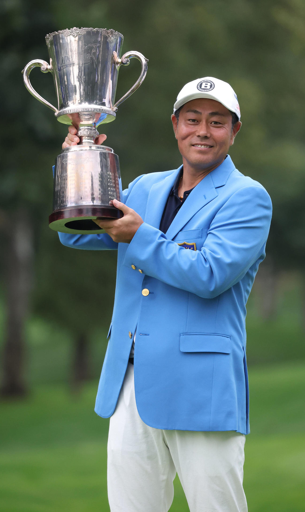 優勝杯を手に笑顔で記念撮影に応じる谷原（撮影・佐藤翔太）