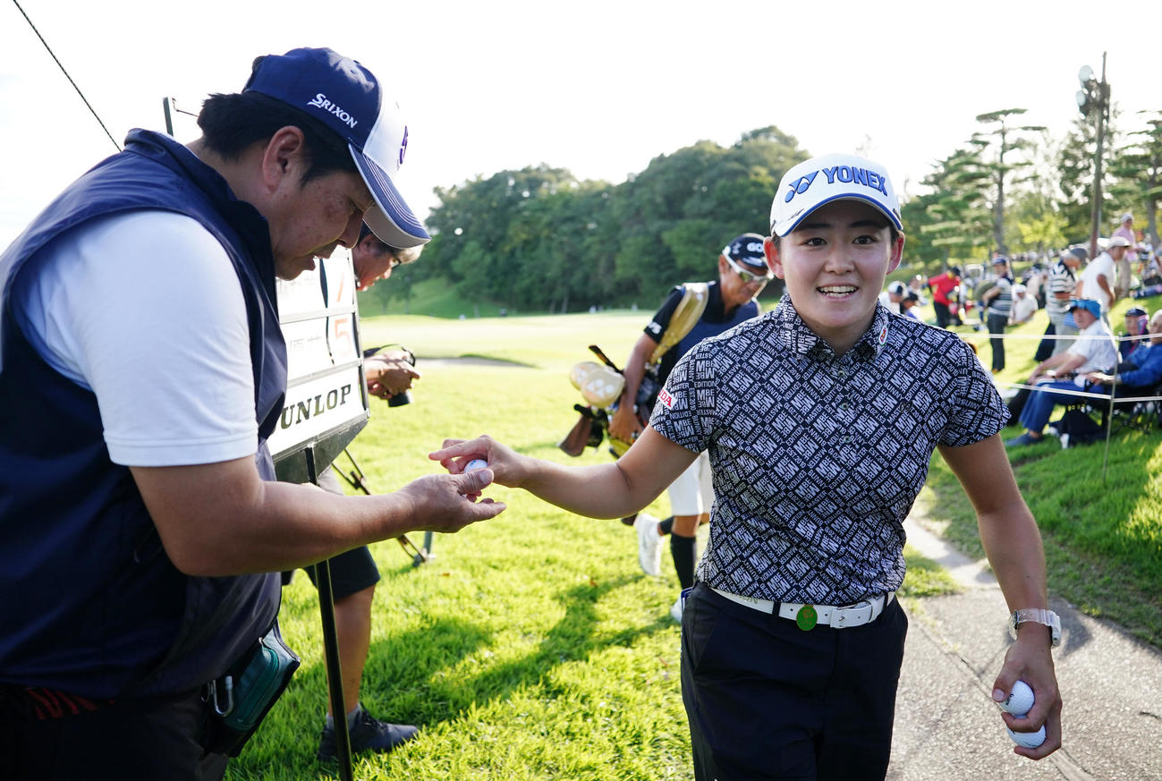 18番、通算10アンダーでホールアウトし、ボランティアへボールを渡す岩井明（撮影・江口和貴）