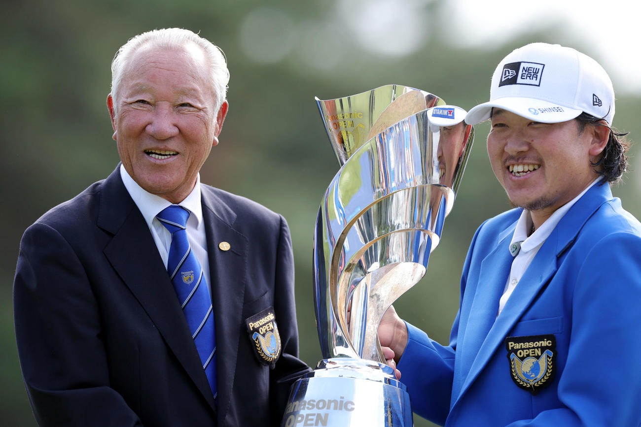 優勝トロフィーを手に笑顔を見せる大槻。左はJGTO青木会長（撮影・前田充）