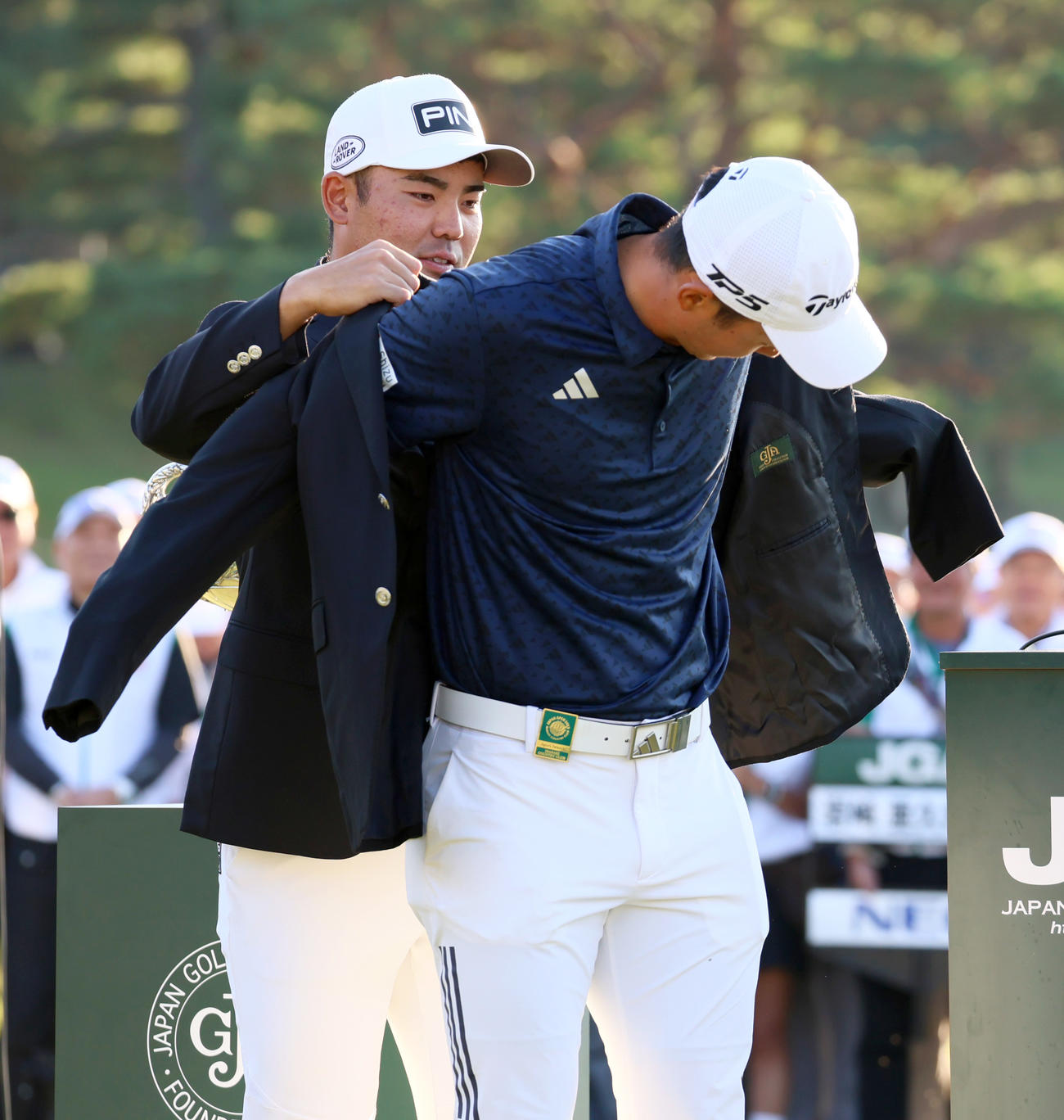 日本オープンゴルフ選手権を制した岩崎（手前）は蝉川から優勝ブレザーを着させてもらう（撮影・上山淳一）
