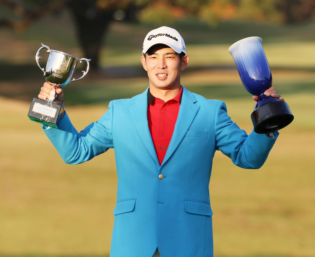 通算24アンダーで優勝し優勝トロフィーとマイナビ杯を掲げる中島（撮影・清水貴仁）