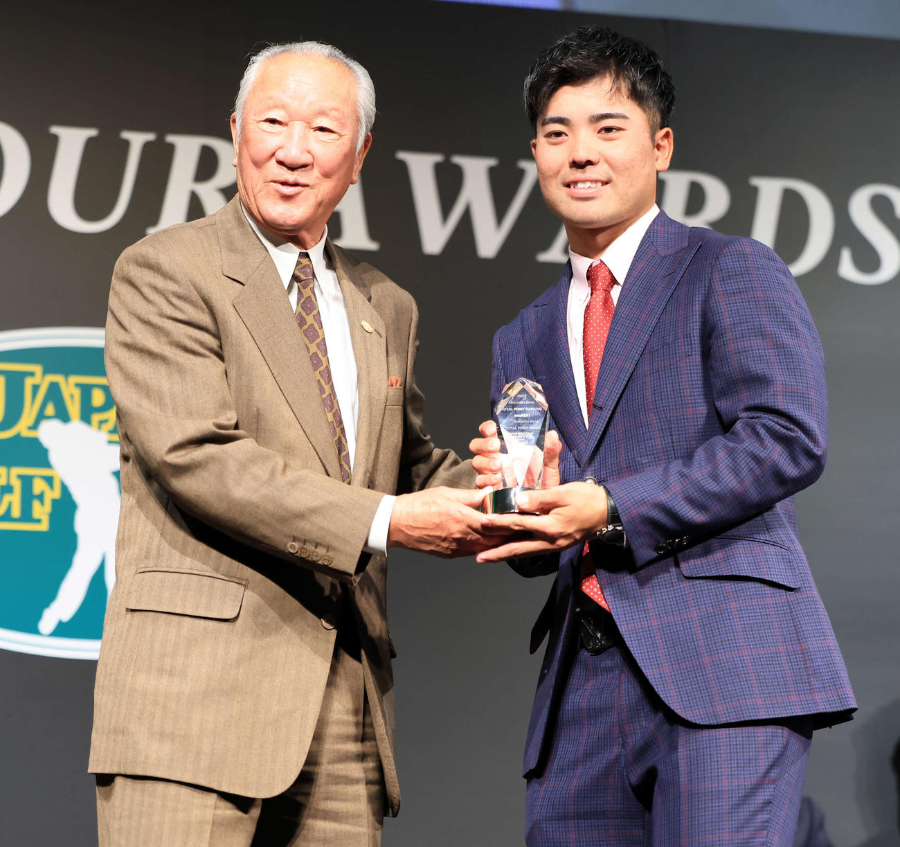 2023年ジャパンゴルフツアー表彰式で、メルセデス・ベンツトータルポイントランキング賞を受賞した蝉川（右）は青木会長からトロフィーを受け取る（撮影・浅見桂子）