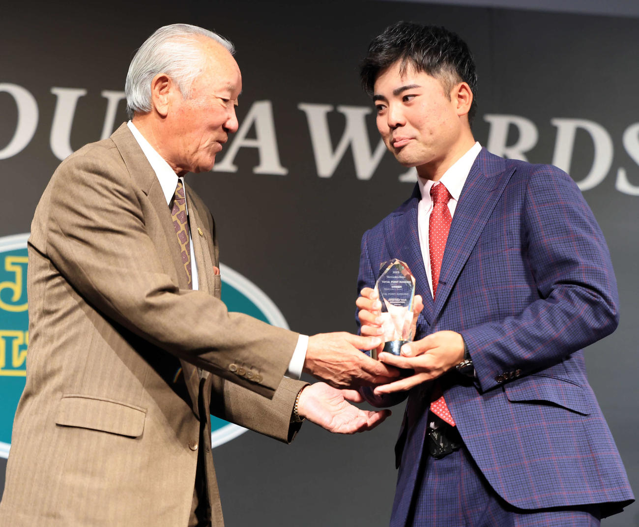 2023年ジャパンゴルフツアー表彰式で、メルセデス・ベンツトータルポイントランキング賞を受賞した蝉川（右）は青木会長からトロフィーを受け取る（撮影・浅見桂子）