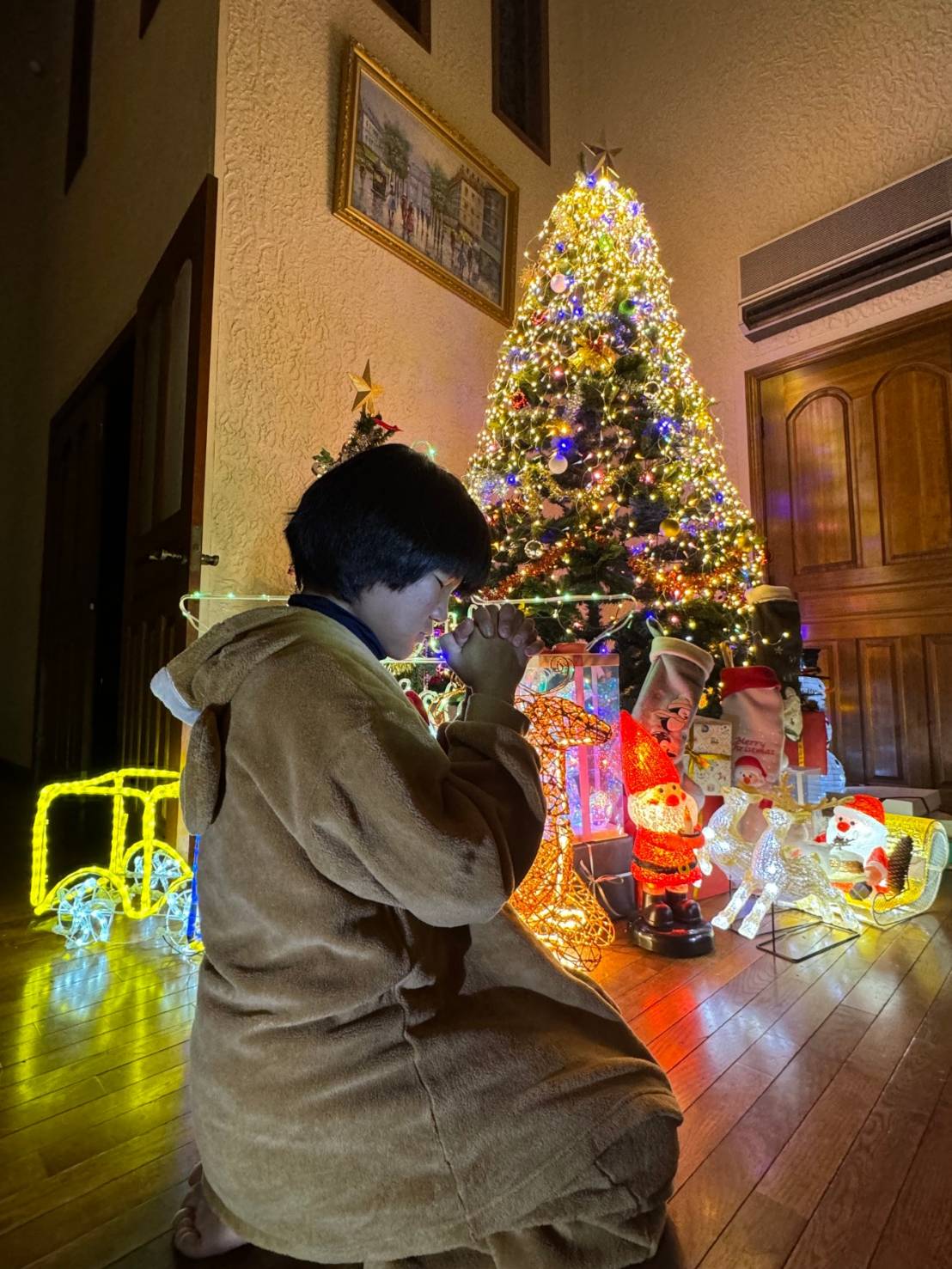 自宅に置かれた巨大クリスマスツリーの前で、母みゆきさんのがん治癒を願う須藤弥勒（父憲一さん提供）