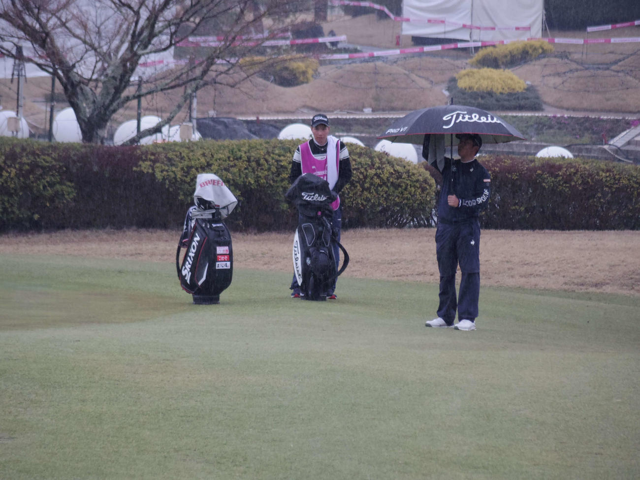 傘を差してコースを回る前田（右）