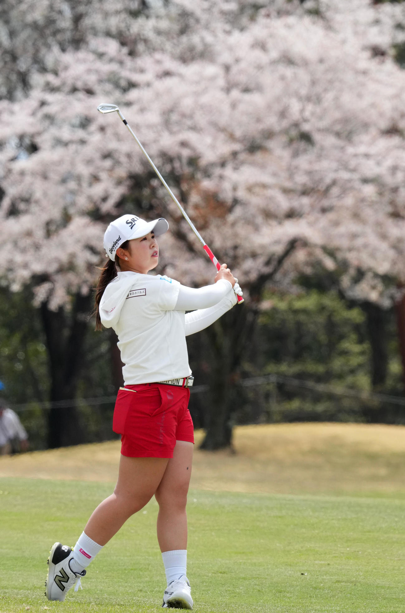 15番、桜を背にショットを放つ山下（撮影・横山健太）