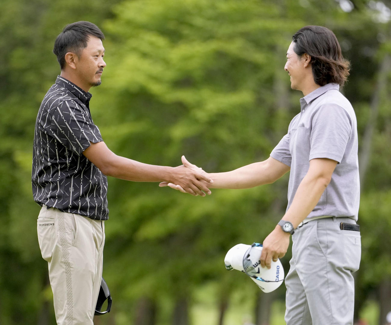 最終日、石川遼（右）とのプレーオフを制し、握手を交わす岩田寛。国内三大大会初制覇を果たした（共同）