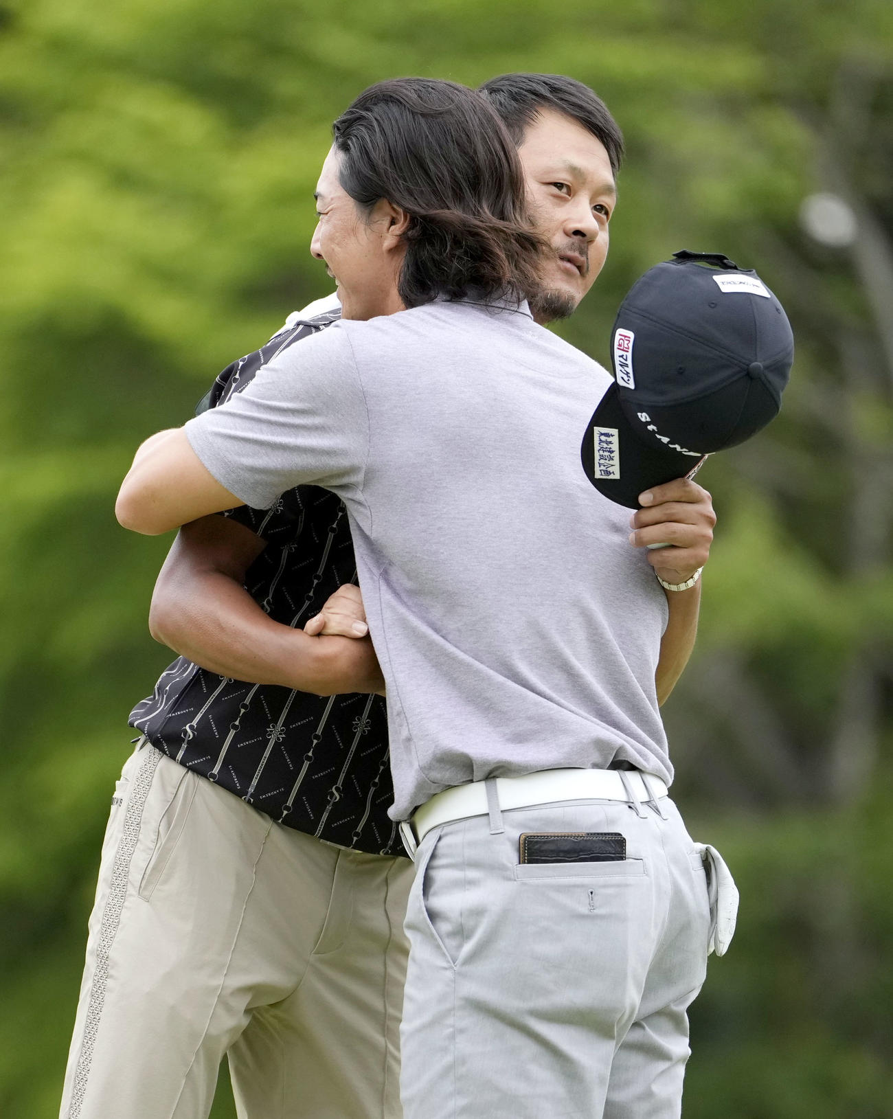 最終日、石川遼（手前）とのプレーオフを制し、健闘をたたえ合う岩田寛。国内三大大会初制覇を果たした（共同）