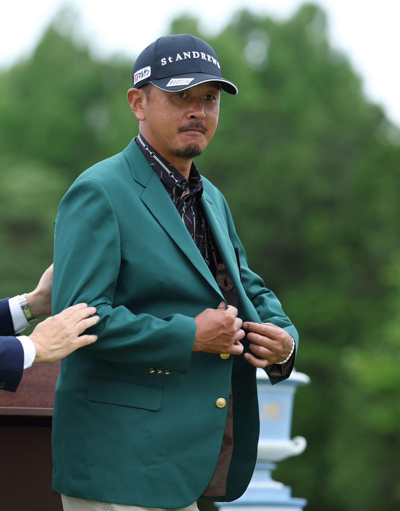 チャンピオンブレザーの袖に腕を通す岩田（撮影・河田真司）