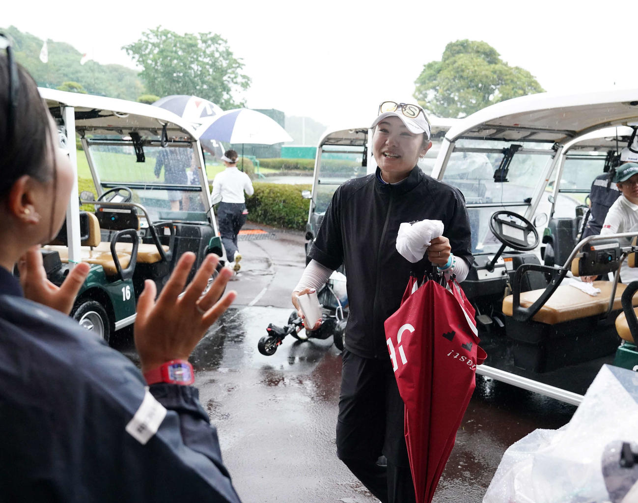 雨天のため競技が一時中断となり、引き揚げてきたクラブハウス前で青木（左）に迎えられる藤田さ（撮影・小沢裕）