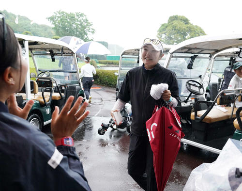 雨天のため競技が一時中断となり、引き揚げてきたクラブハウス前で青木（左）に迎えられる藤田さ（撮影・小沢裕）