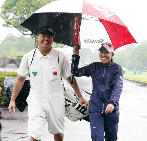 雨天のため競技が一時中断となりキャディーを務める夫に傘をさしてクラブハウスに引き揚げてきた中山（撮影・小沢裕）