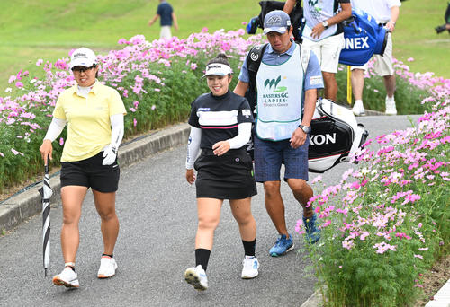 16番ホール、コスモスが咲く橋を渡りセカンドに向かう左から畑岡奈紗（左）と山下美夢有（撮影・和賀正仁）