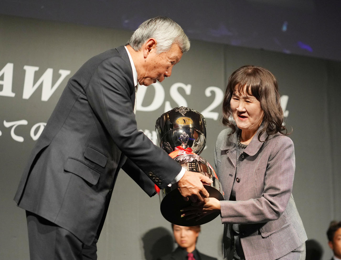 金谷が最優秀選手賞を受賞し代理でトロフィーを受け取る母・美也子さん。左は諸星裕会長（撮影・横山健太）